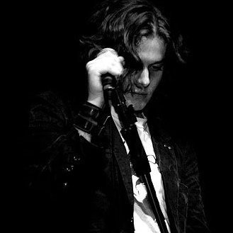 A black and white image of Damian on stage holding a microphone.