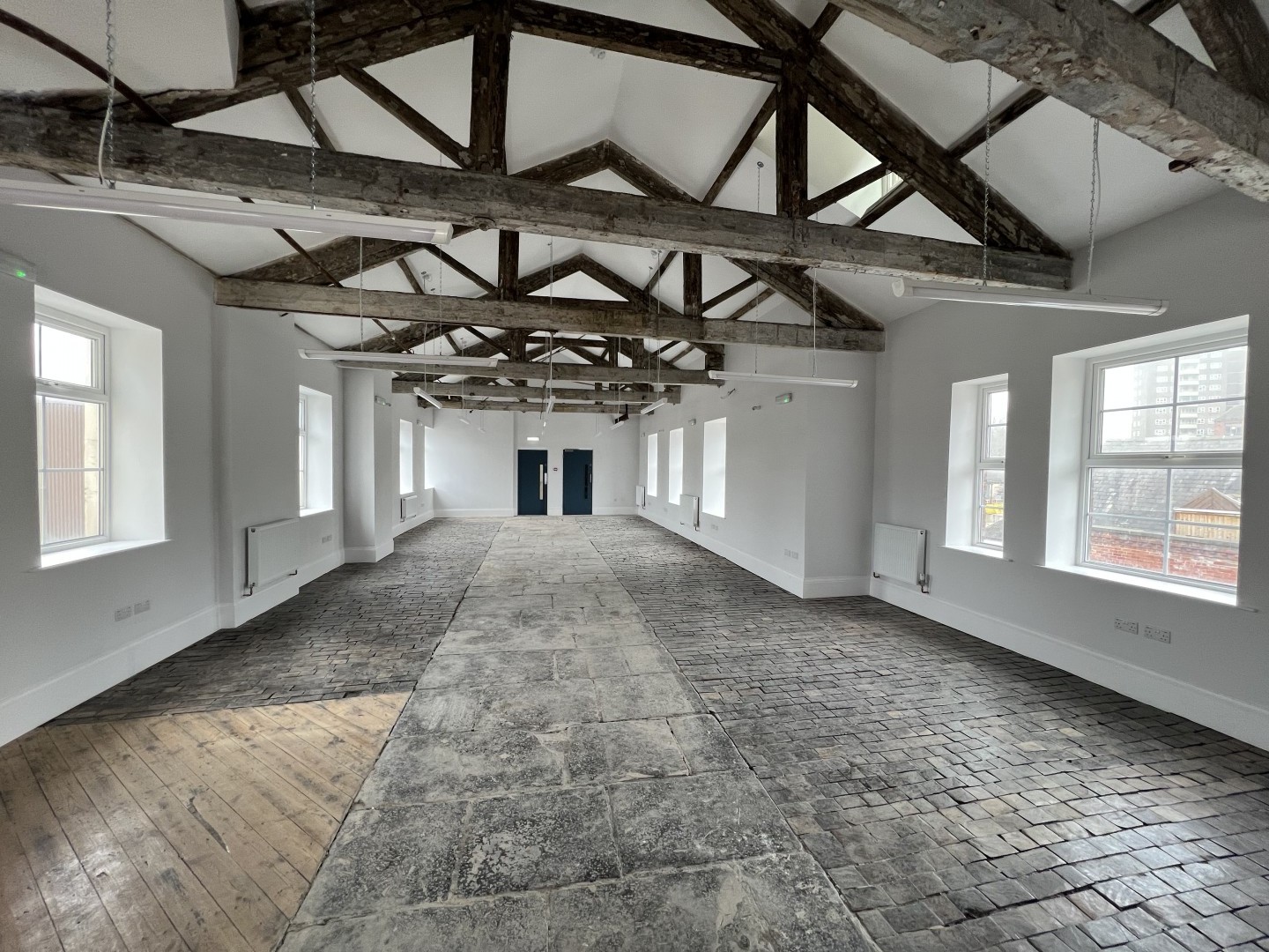An image showing what the inside of the space looks like for MAP Charity. Including a slightly upward shot of the oak trusses and the going installation of the flooring.