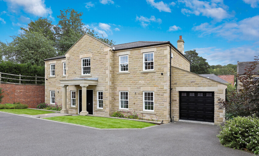 An exterior shot of the Georgian-style home which is located in Ossett, Wakefield. The property includes a double doorway, two stone pillar posts, eleven windows on the front of the building and a garage to the right hand side of the property.