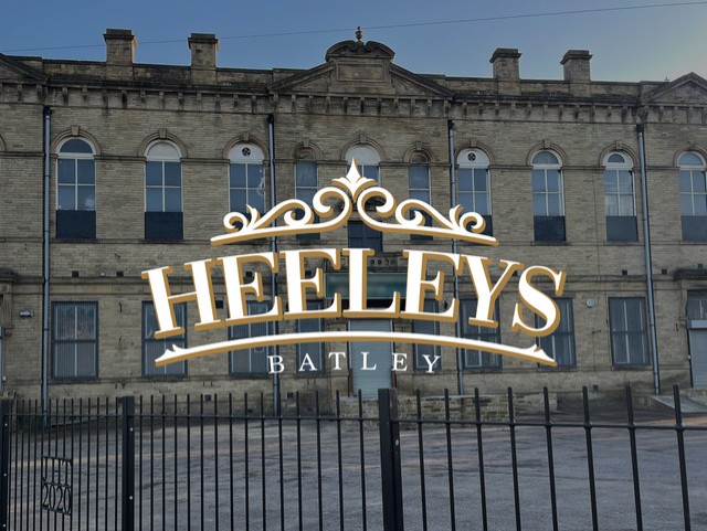 An image of the new Heeley's logo that is over a darker image of the building. The white writing gives a nice contrast to the background image.